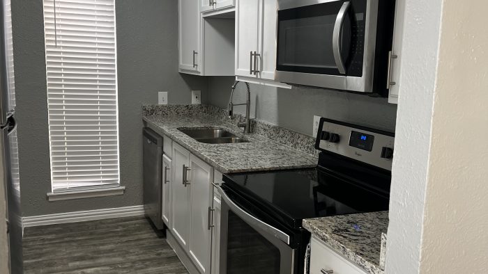 a kitchen with stainless steel appliances and white cabinets at The Calypso Court